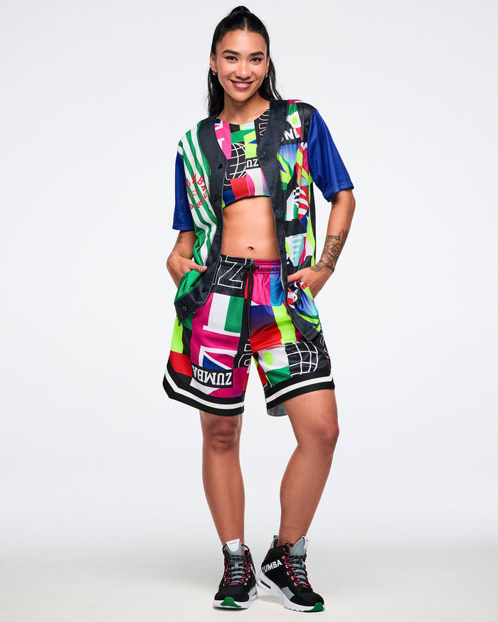 Female model wearing a colorful outfit with a patterned bra and shorts on a white background.