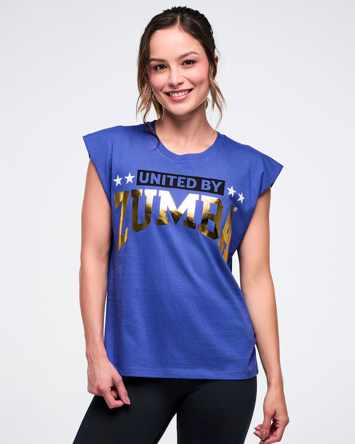 Female model in a blue “United by Zumba” top with “Zumba” in gold text, set against a white background.