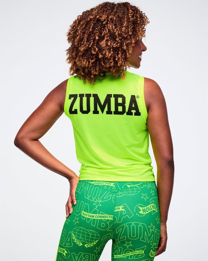 Back view of a female model in a neon yellow tank with bold black “Zumba,” text, paired with green patterned leggings on a white background.