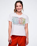 Female model in a white Zumba T-shirt with “Zumba” repeated three times, “Rhythm Connection” in black beneath, and a colorful globe icon on the back, set against a white background.