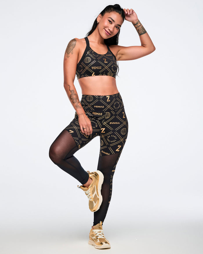Full view of female model wearing a black and gold sports bra and matching leggings with geometric patterns.