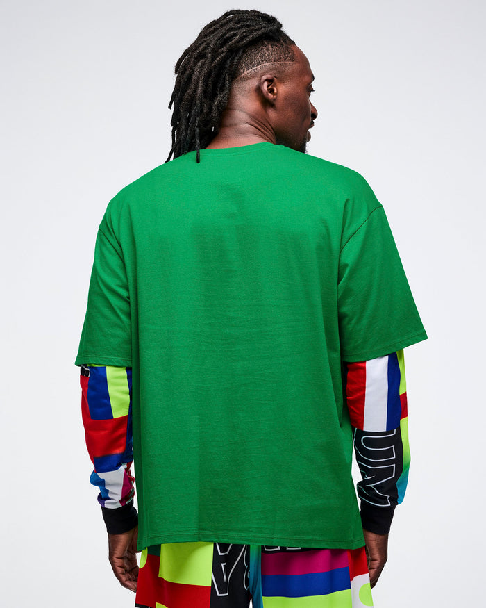 Back view of a male model wearing a green shirt over another shirt with colorful sleeves, on a white background.