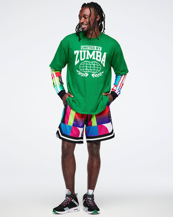 Male model wearing a green Zumba shirt and colorful shorts on a white background.