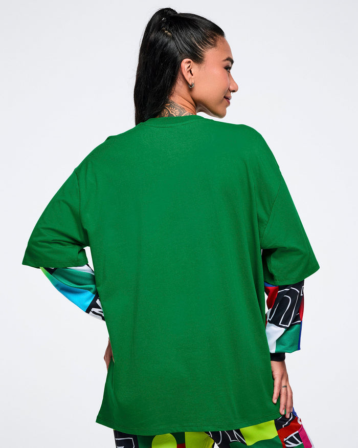 Back view of a female model wearing a green oversized t-shirt on a white background.