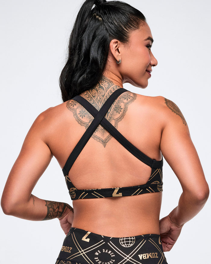 Back view of a female model wearing a black cross-strap bra with a geometric pattern and gold accents against a plain background.