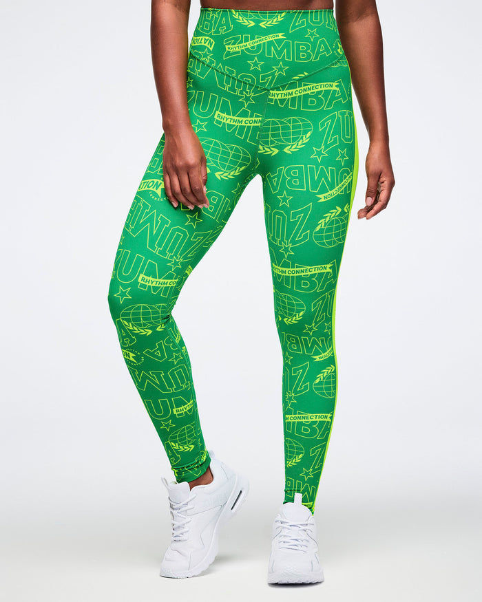 Female model wearing green leggings with Zumba text pattern worn by a person on a white background.