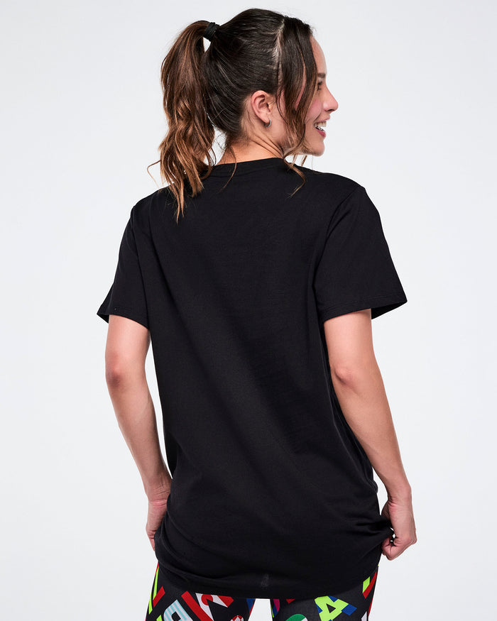 Back view of female model wearing a black t-shirt with colorful leggings on a white background.
