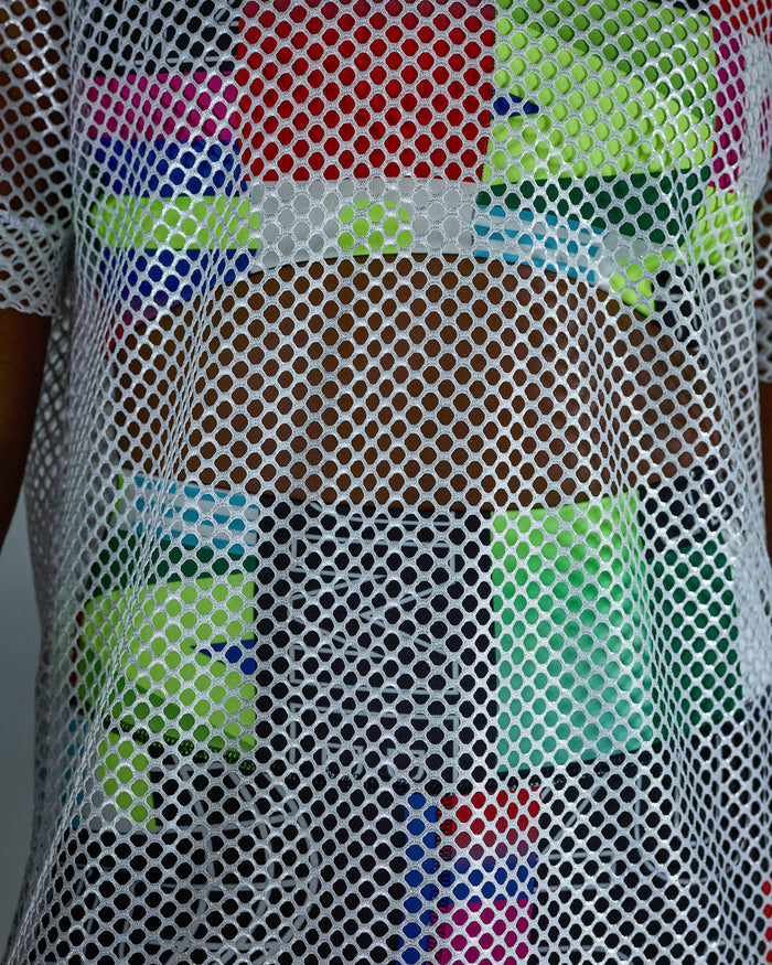 Close-up of the silver mesh fabric with multicolored patterns of an outfit underneath.