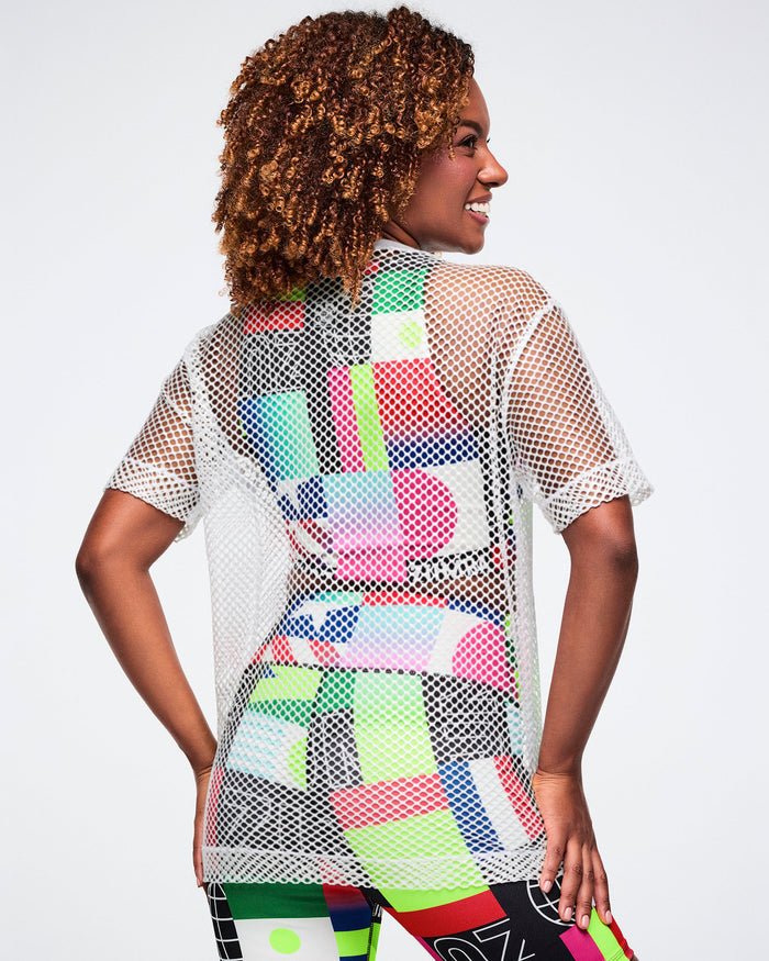 Back view of a female model in a colorful bra and biker shorts, layered with a silver mesh top, set against a white background.