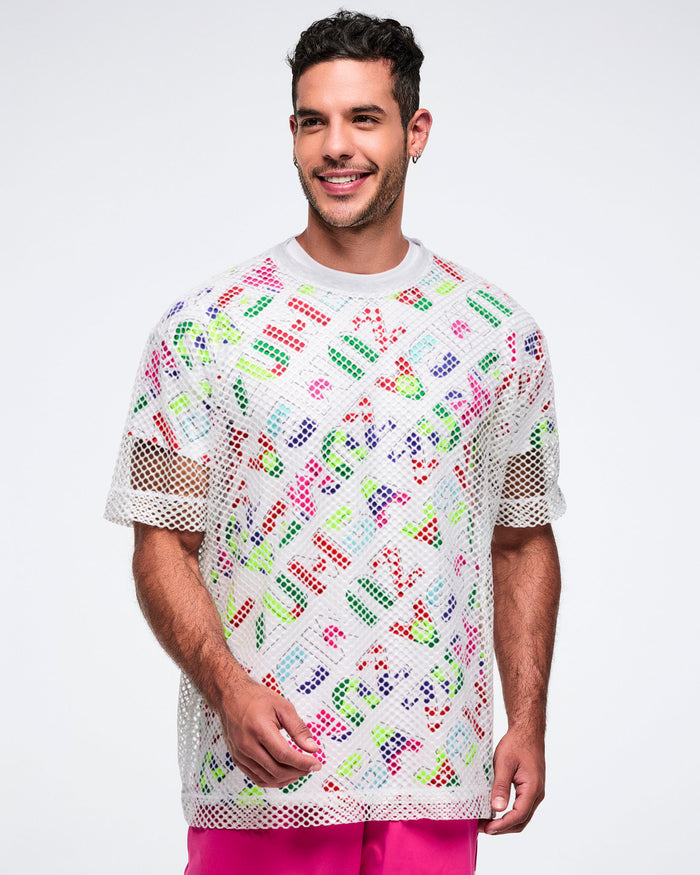 Male model wearing a patterned shirt layered with a silver mesh top and paired with pink pants, set against a white background.