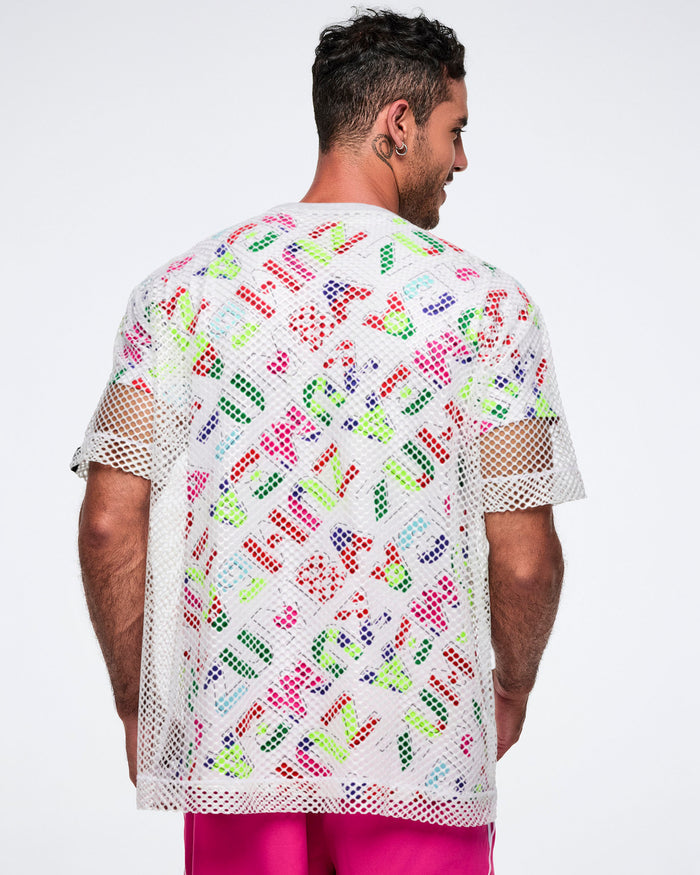 Back view of a male model wearing a colorful patterned shirt with a silver mesh top layered over it, paired with pink pants.