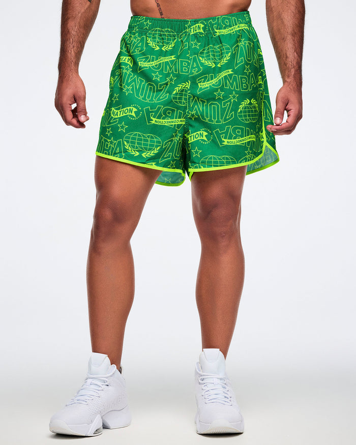 Male model wearing green shorts with yellow text and patterns on a white background.