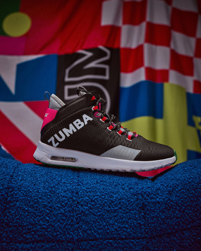 Black Zumba sneaker on a blue surface with a colorful background.