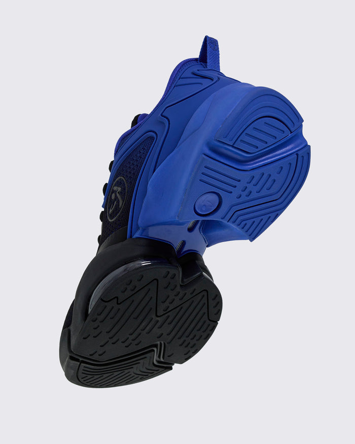 Blue-and-black Zumba sneaker, angled sole view showing textured black outsole and blue midsole details.