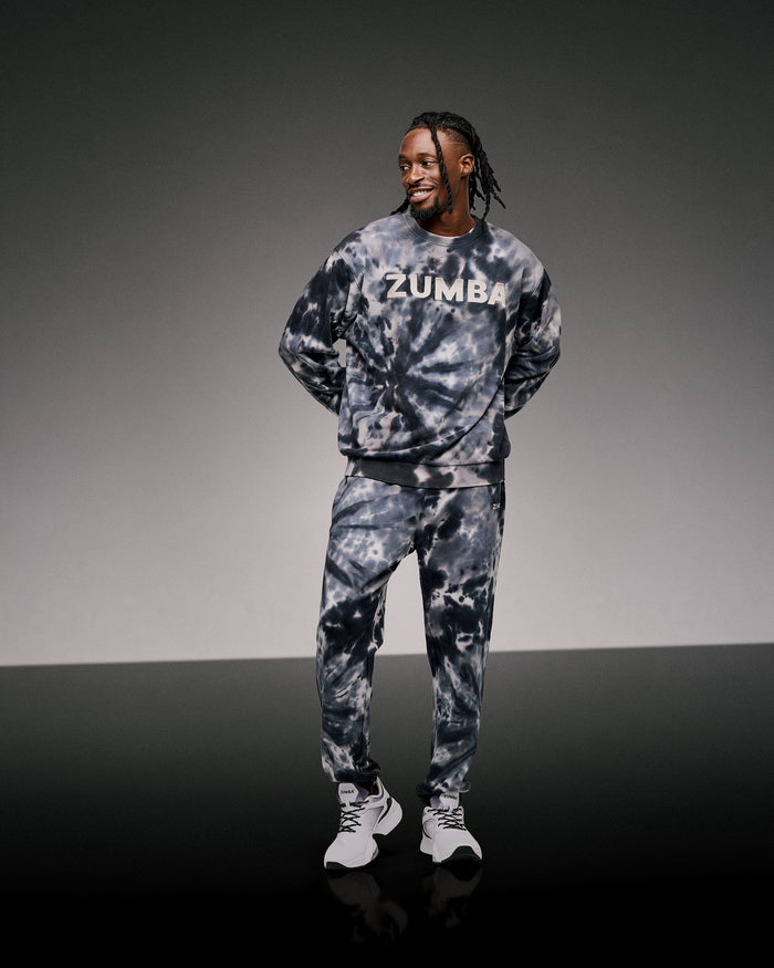 Male model wearing a Zumba tie-dye outfit on a gray background.