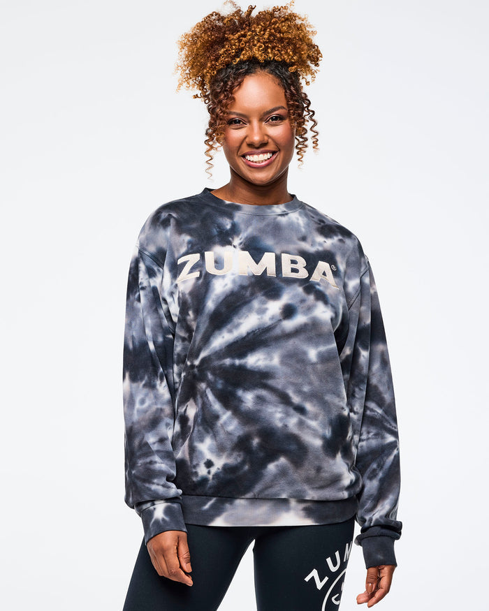 Female model wearing a Zumba tie-dye sweatshirt on a light gray background.