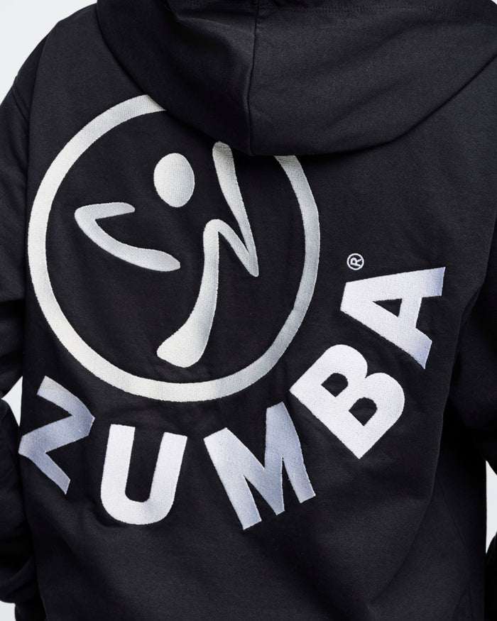 Close-up back view of a black hoodie featuring an embroidered white Zumbito logo with arched "ZUMBA" text below, against a white background.