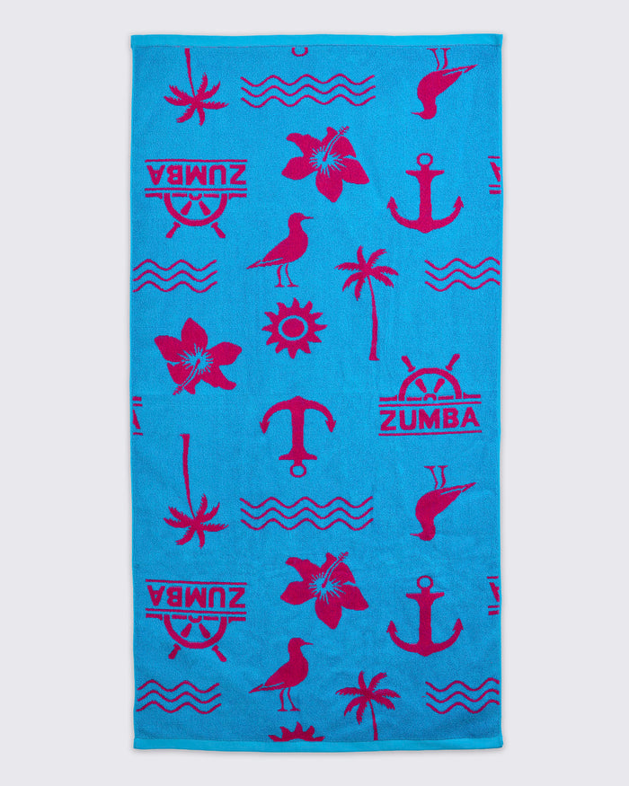 Turquoise beach towel with hot-pink Zumba logo and allover nautical icons, including anchors, palm trees, waves, flowers, and birds, laid flat on a white background.