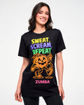 Female model wearing a black graphic tee with a colorful "Sweat (yellow), Scream (purple), Repeat (green)" print and a dancing pumpkin character in orange and "ZUMBA" text in pink below.