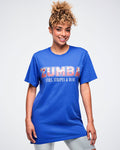 Female model wearing a blue Zumba T‑shirt with red‑and‑white stars and stripes, plus “stars, stripes & dance” text below against a white background.