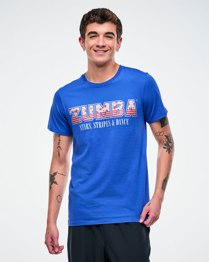 Male model wearing a blue Zumba t-shirt with red‑and‑white stars and stripes, plus “stars, stripes & dance” text below against a white background.