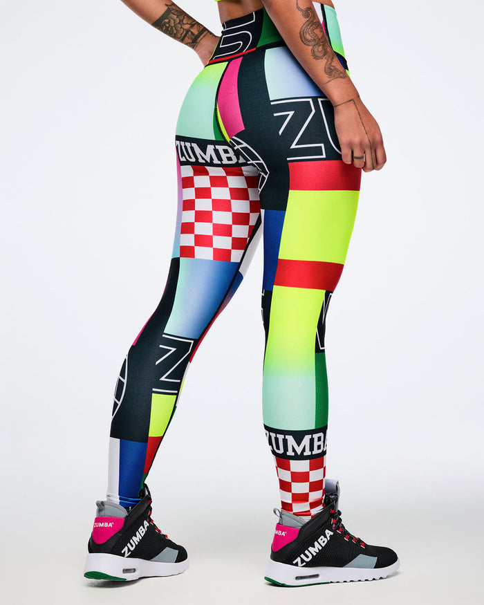 Back view of colorful patterned leggings with Zumba branding worn by a female model on a white background.